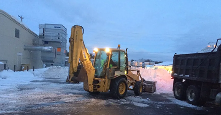 Backhoe with snow plow attachment at dusk